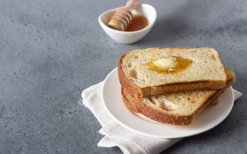 Tranches de pain grillé et beurre au miel sur fond de pierre grise
 - Photo, image
