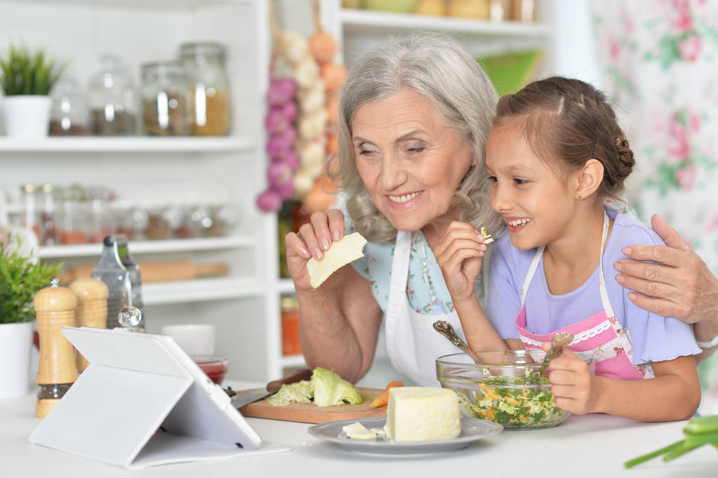 Senior vrouw met kleindochter diner bereiden in de keuken - Foto, afbeelding
