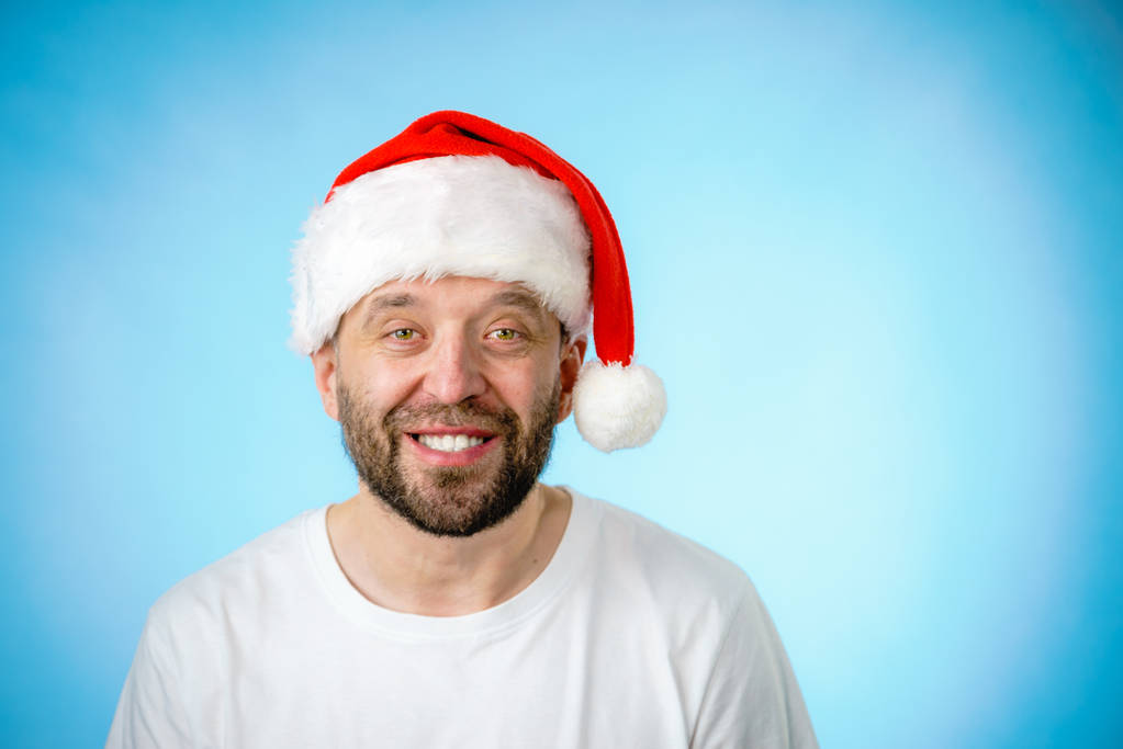 コピー スペース ブルーでサンタ クロースの帽子の肖像画、身に着けているひげを生やした男。クリスマスの時期. - 写真・画像