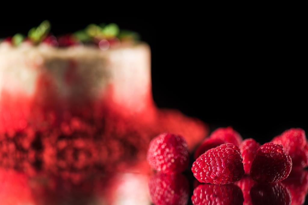selective focus of white cake decorated with red currants and mint leaves near raspberries isolated on black - Photo, Image