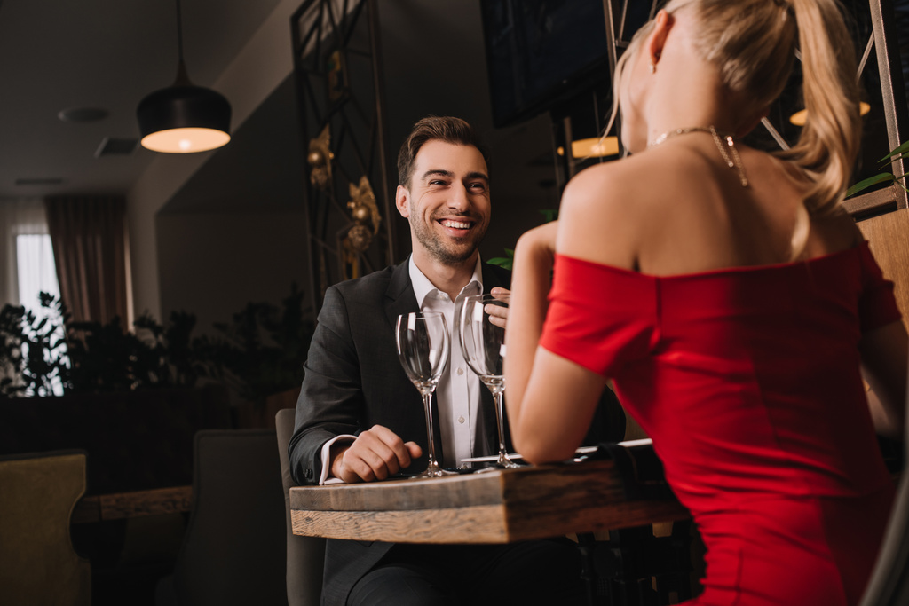 bel fidanzato guardando la fidanzata in abito rosso durante la cena
 - Foto, immagini