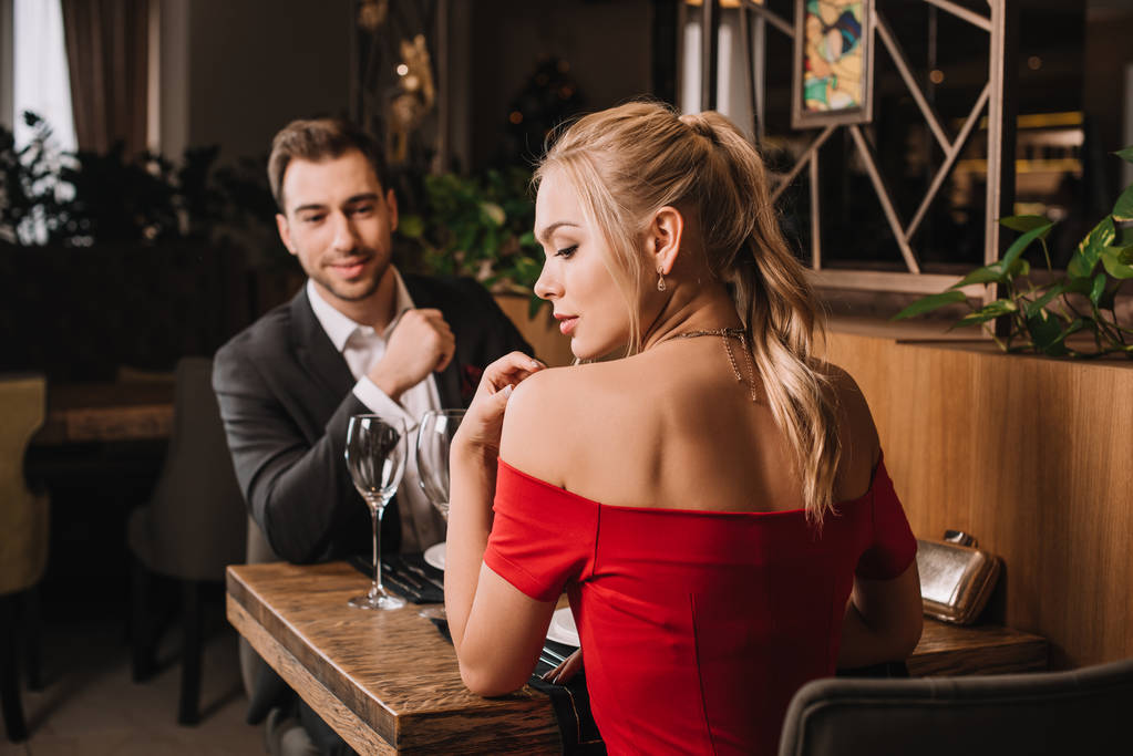 レストランで赤いドレスの魅力的なガール フレンドを見てハンサムな彼氏 - 写真・画像