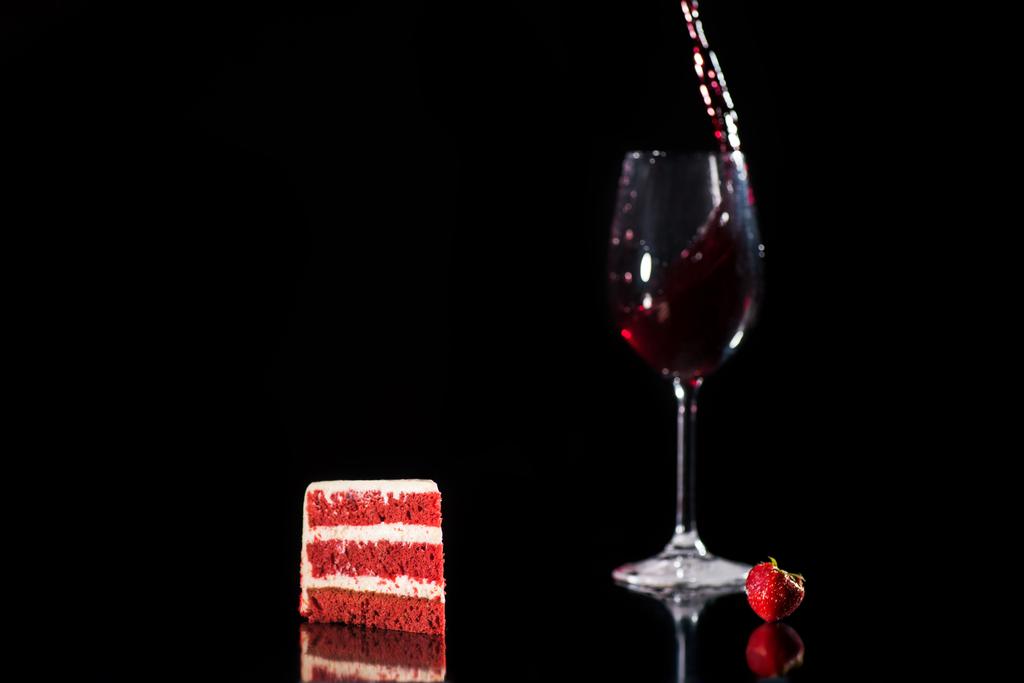 kus červenobílý dort u sklenky vína, samostatný na černém - Fotografie, Obrázek