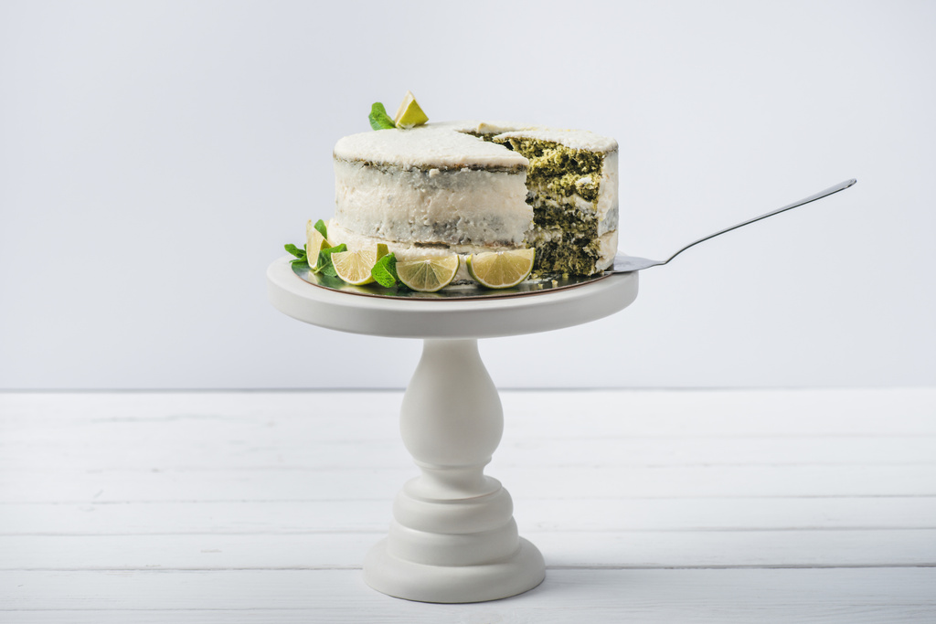 gâteau blanc décoré avec des feuilles de menthe et des tranches de ligne sur support isolé sur blanc
 - Photo, image