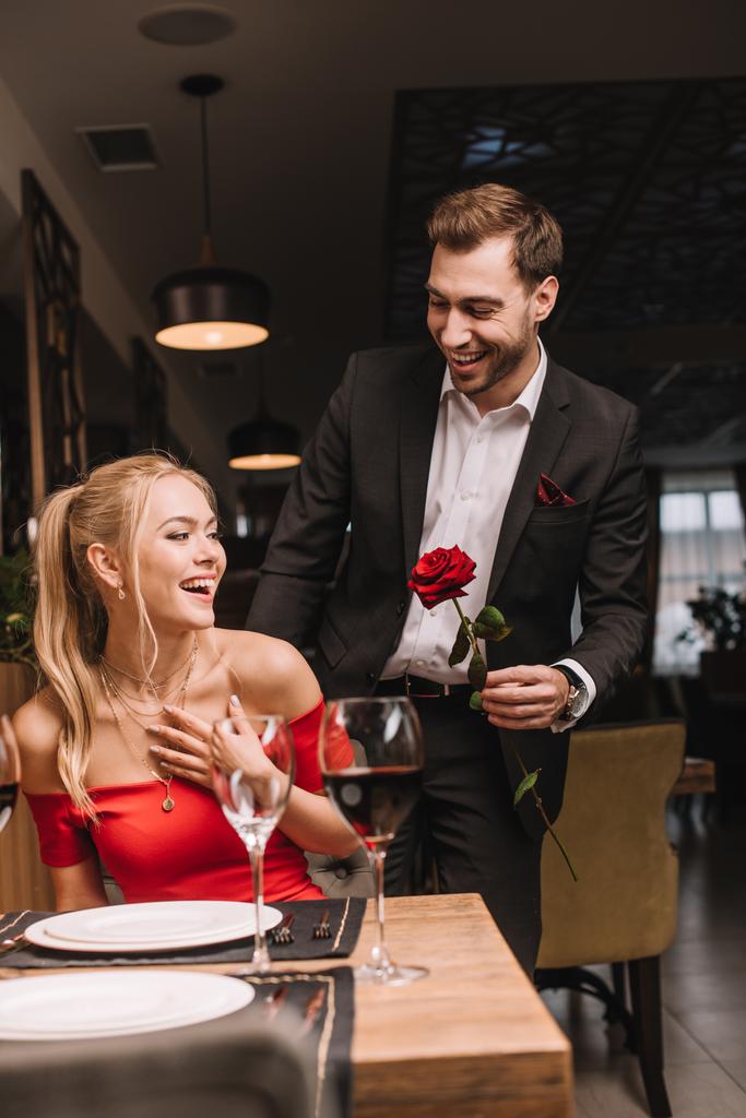 petit ami joyeux donnant rose rouge à petite amie surprise dans le restaurant
  - Photo, image