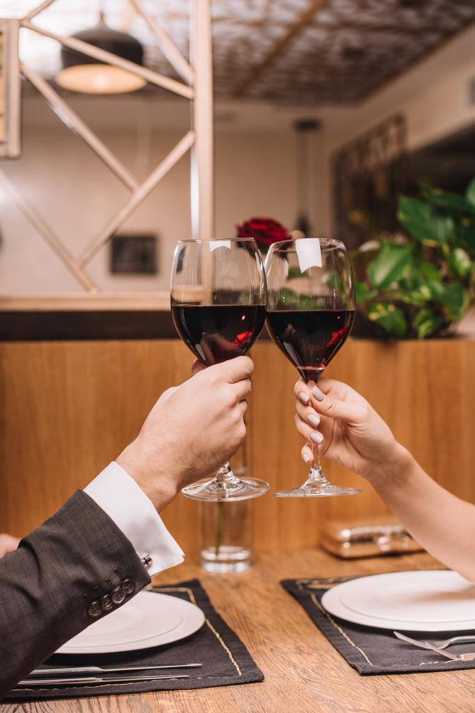 vista recortada de pareja tintineo con copas de vino tinto durante la cita romántica
 - Foto, Imagen