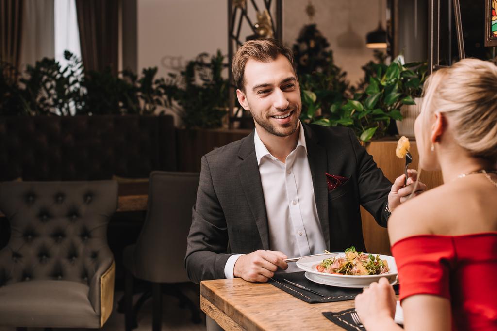 красивый парень кормит девушку свежим салатом в ресторане
  - Фото, изображение