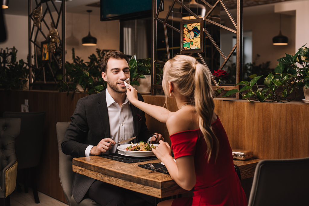 novia limpiando la boca de guapo novio con servilleta en restaurante
  - Foto, Imagen