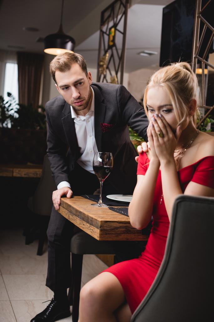 レストランで心配して彼氏の近く泣いている金髪の女性の選択と集中  - 写真・画像