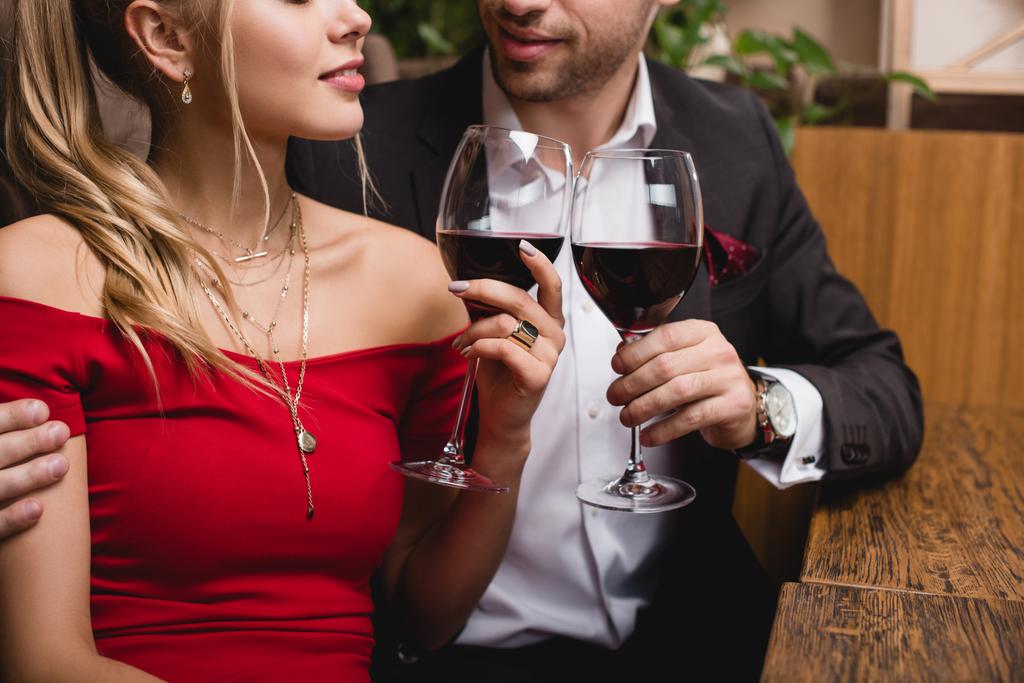 καλλιεργημένη άποψη του άνδρα και της γυναίκας κρατώντας ποτήρια με κόκκινο κρασί  - Φωτογραφία, εικόνα