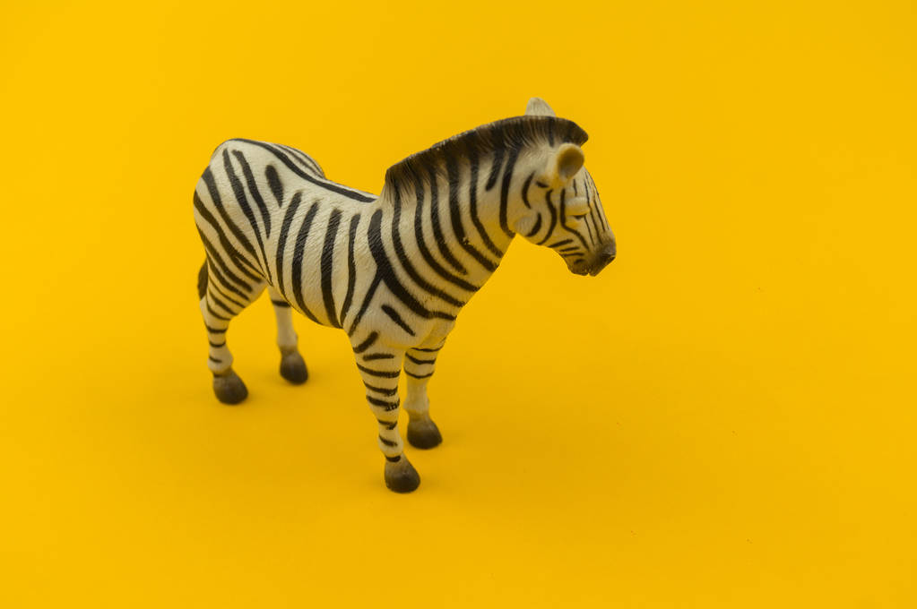 Spielzeug-Zebra aus Plastik auf gelbem Hintergrund. afrikanisches Tier für ein Kind. Ort zum Schreiben. - Foto, Bild