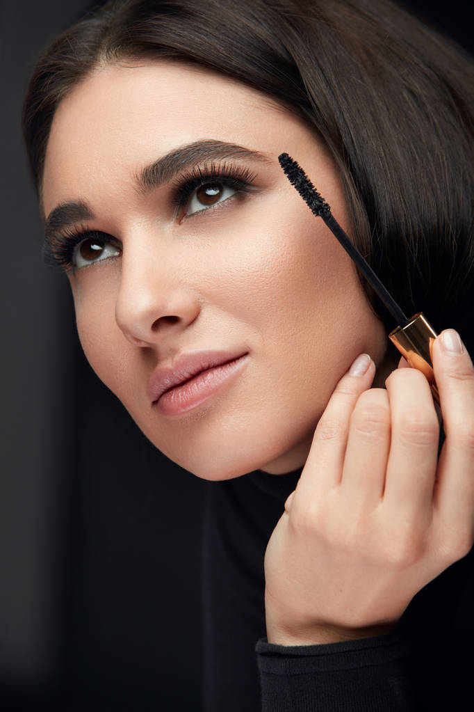 Wimperntusche Make-up. weibliches Schönheitsmodel, das schwarze Wimperntusche mit Pinsel auf lange Wimpern aufträgt. hohe Auflösung - Foto, Bild