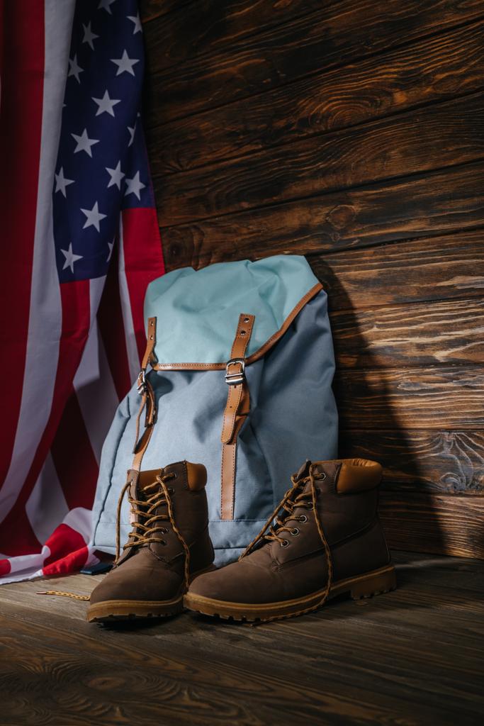 bottes de trekking, sac à dos et drapeau américain sur surface en bois, concept de voyage
  - Photo, image