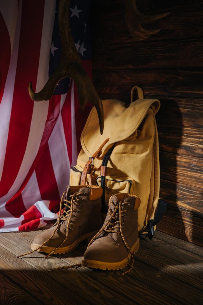 çizme, sırt çantası, boynuzları ve Amerikan bayrağı ahşap yüzeyde trekking - Fotoğraf, Görsel
