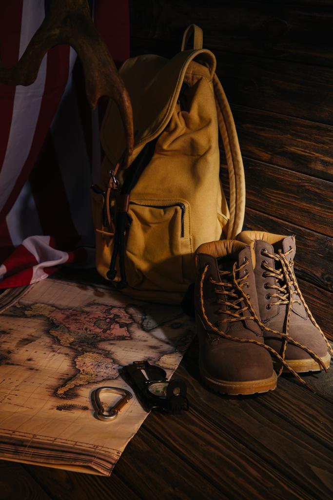 vista ravvicinata di scarponi da trekking, attrezzatura da trekking, mappa, zaino e bandiera americana su superficie in legno
 - Foto, immagini