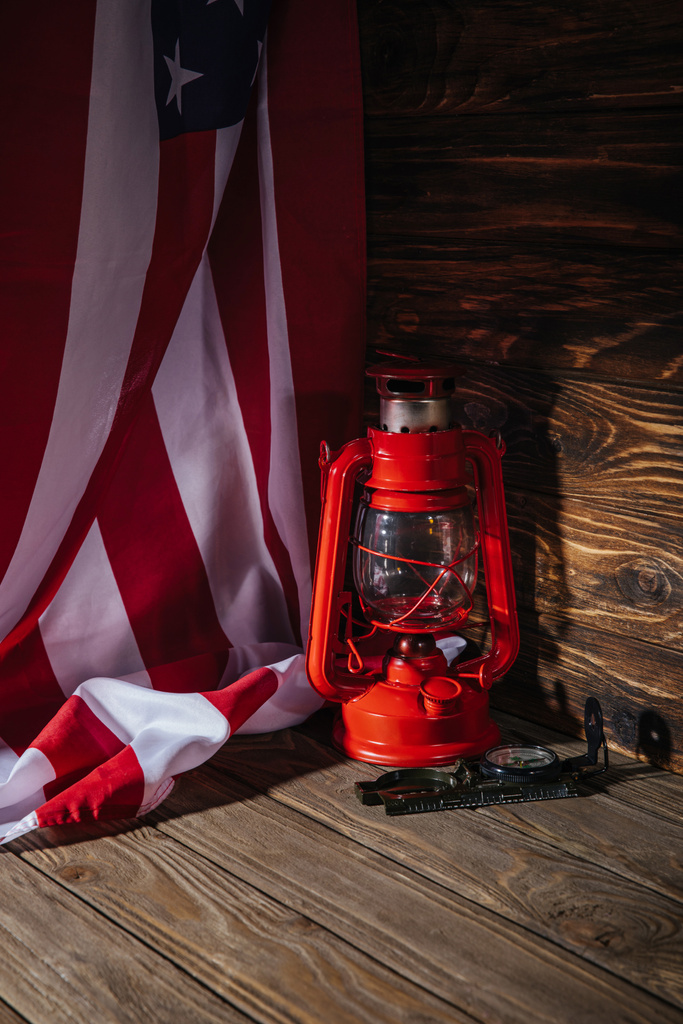 Nahaufnahme von amerikanischer Flagge, roter Laterne und Kompass auf Holzoberfläche  - Foto, Bild