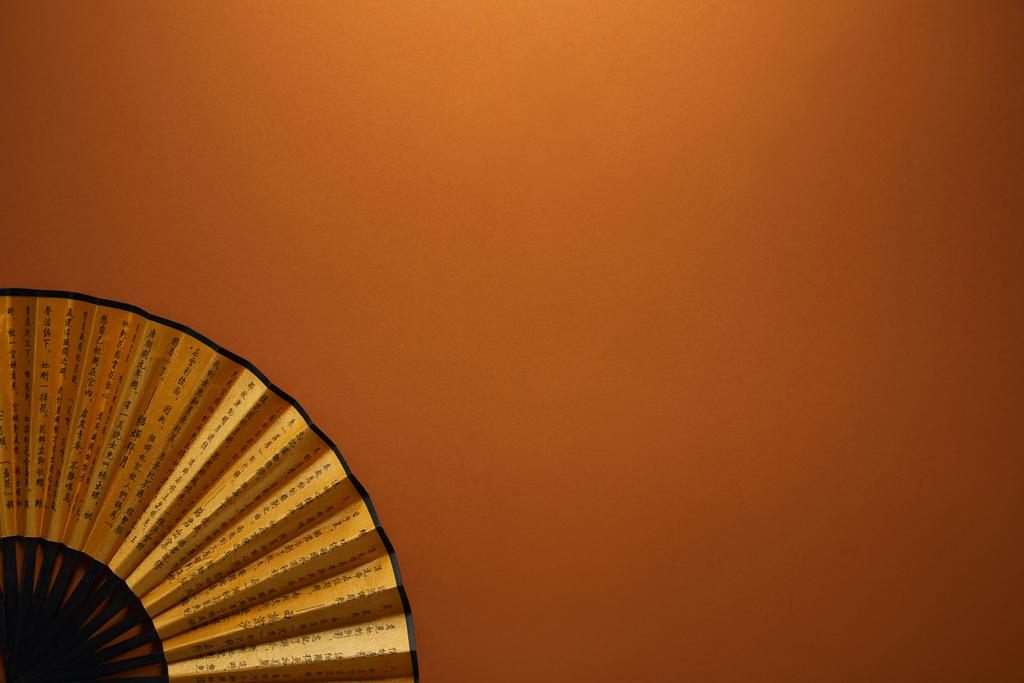 vergrote weergave van decoratieve zwarte en gouden fan met hiërogliefen op bruine achtergrond - Foto, afbeelding
