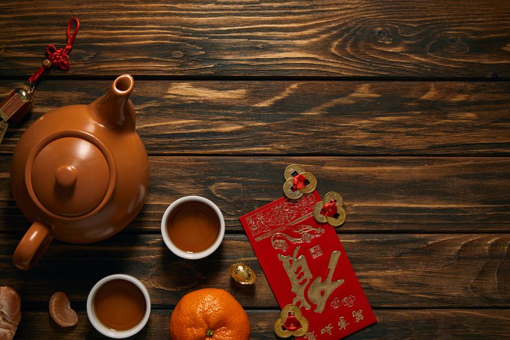 Draufsicht auf Teeservice und traditionelle Dekorationen auf Holztisch, chinesische Neujahrskomposition - Foto, Bild
