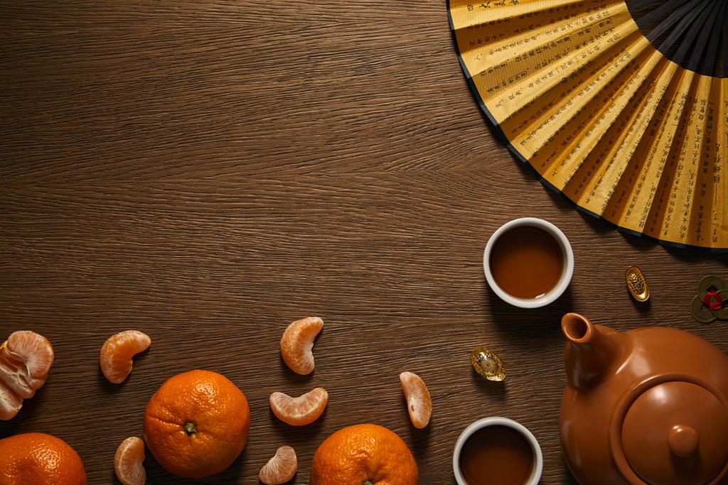 Widok z góry zestaw do herbaty, mandarynki, wentylator i monet na powierzchni drewnianych  - Zdjęcie, obraz