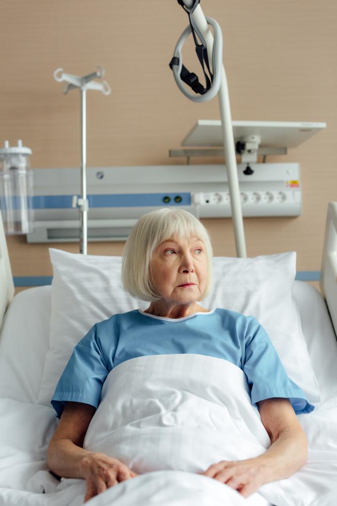 senior woman lying in bed in hospital and looking away - Photo, Image