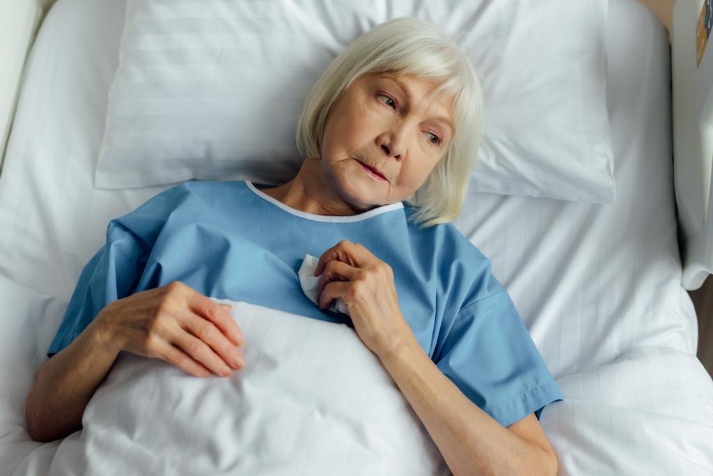 surullinen yksinäinen vanhempi nainen makaa sairaalassa sängyssä
 - Valokuva, kuva