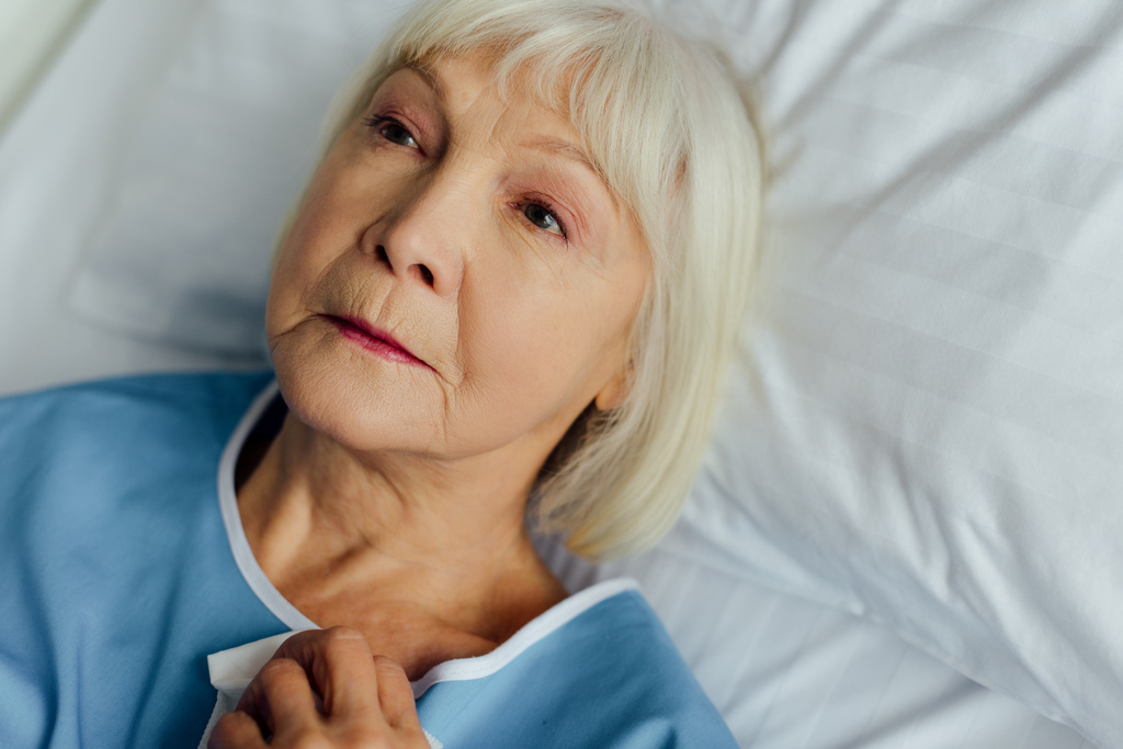 triest senior vrouw met grijze haren liggend in bed in het ziekenhuis - Foto, afbeelding