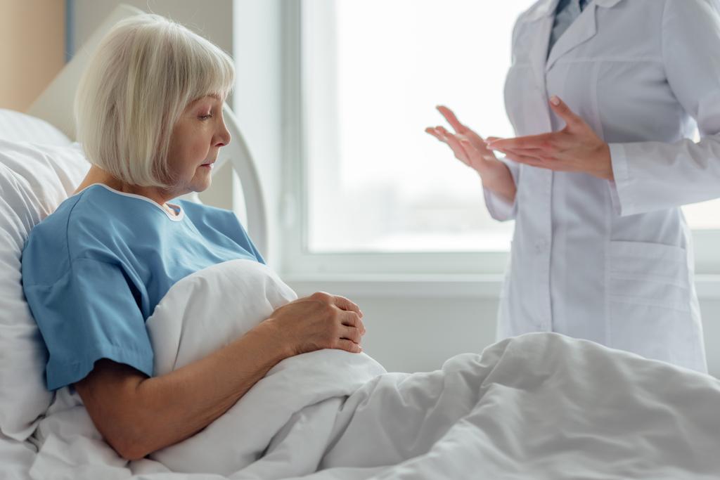 lekarka konsultacji smutny starszy kobieta z siwe włosy, leżącego w łóżku szpitalnym - Zdjęcie, obraz