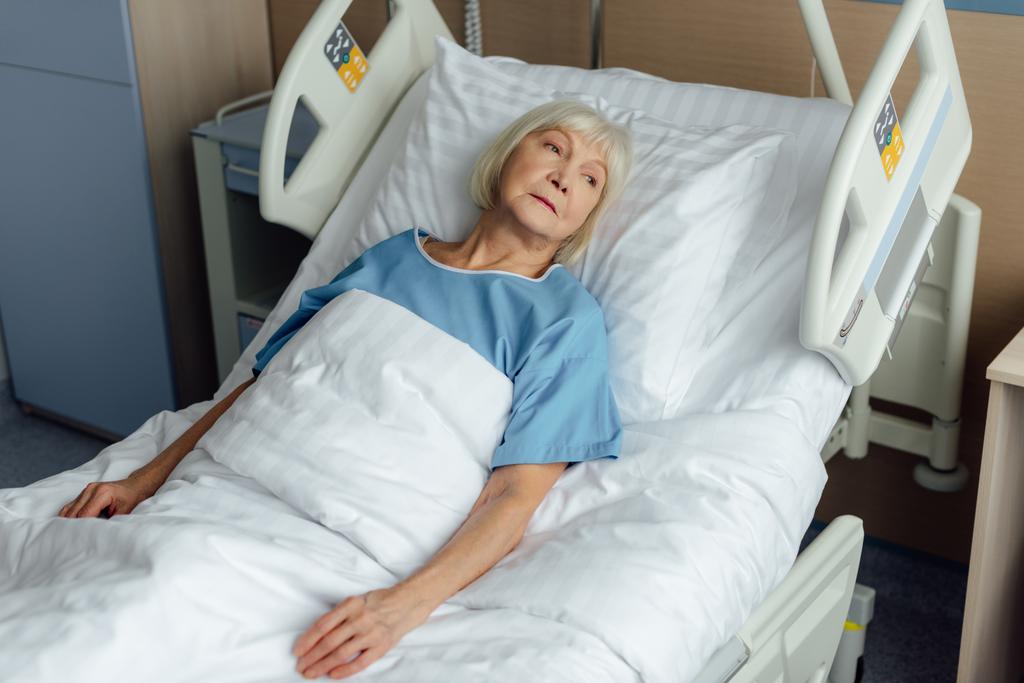 病院のベッドで横になっている悲しい孤独なシニア女性 - 写真・画像