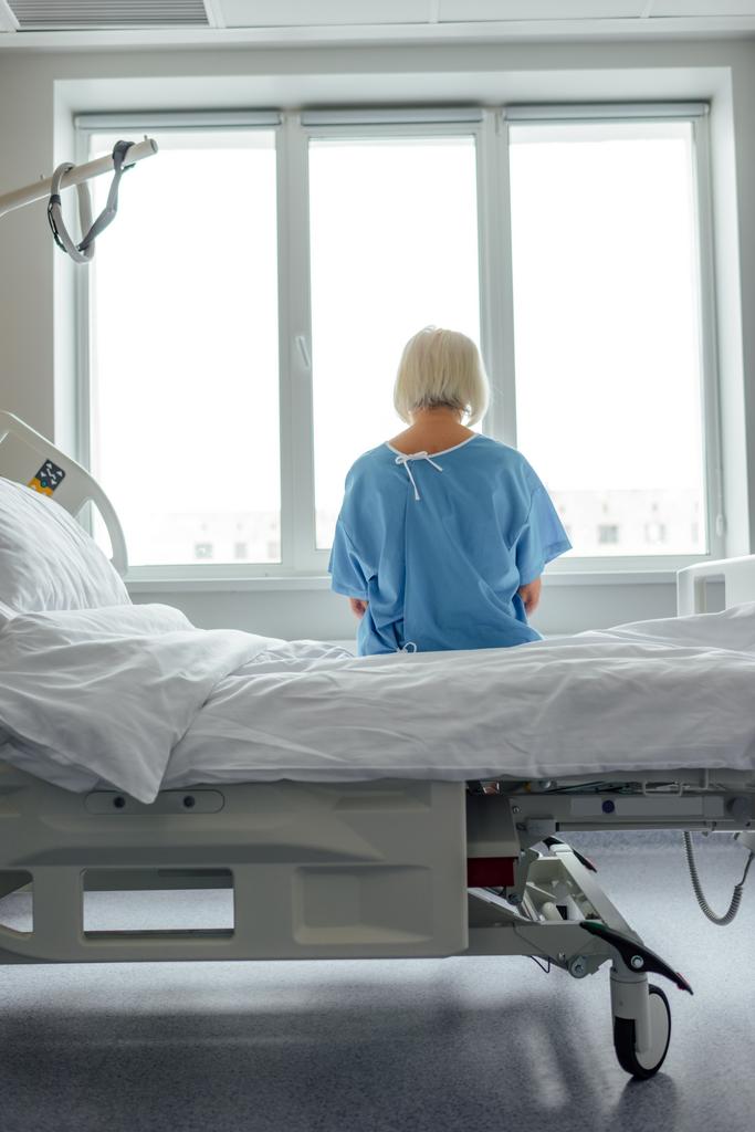 Rückansicht einsamer Seniorin auf Krankenhausstation  - Foto, Bild
