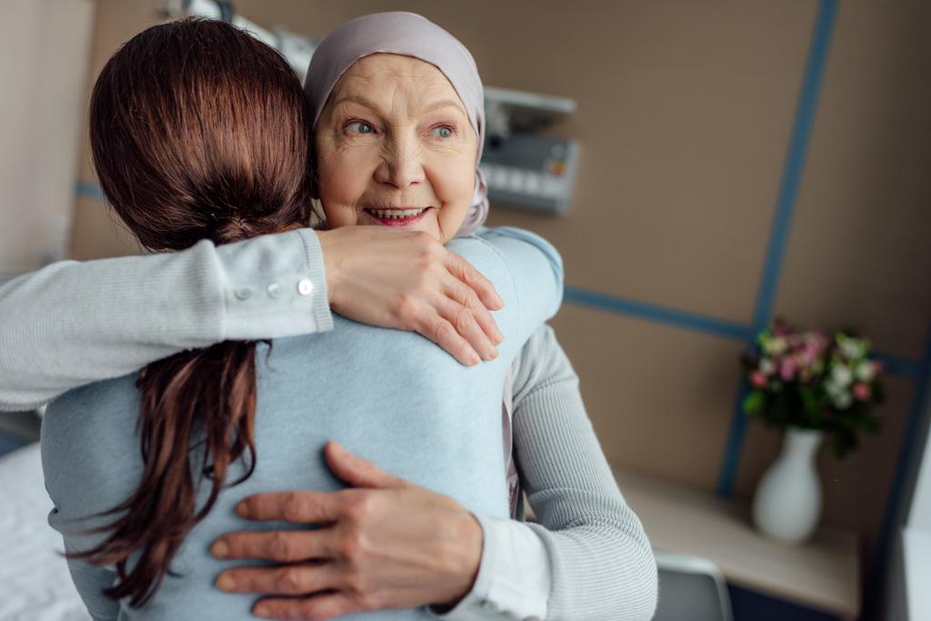 усміхнена старша жінка в хустці обіймає дочку в лікарні
 - Фото, зображення