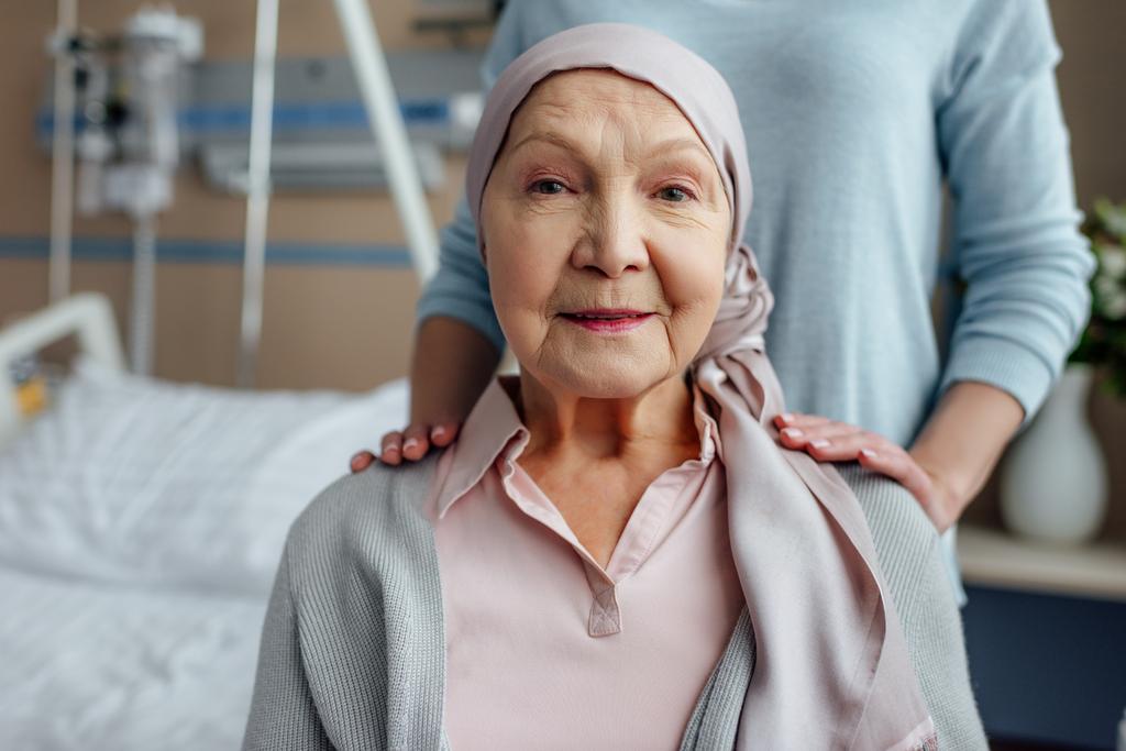 mujer mayor en pañuelo con hija en el fondo en el hospital
 - Foto, Imagen
