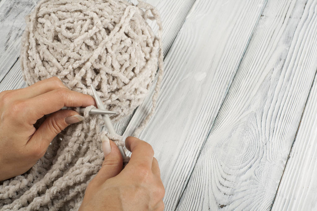 木製テーブルの上の編み物の針の手のクローズ アップ - 写真・画像