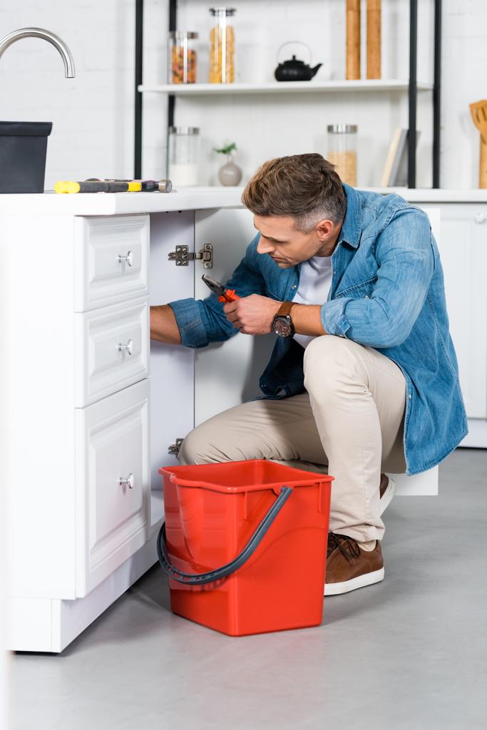 schöner erwachsener Mann repariert Küchenspüle  - Foto, Bild