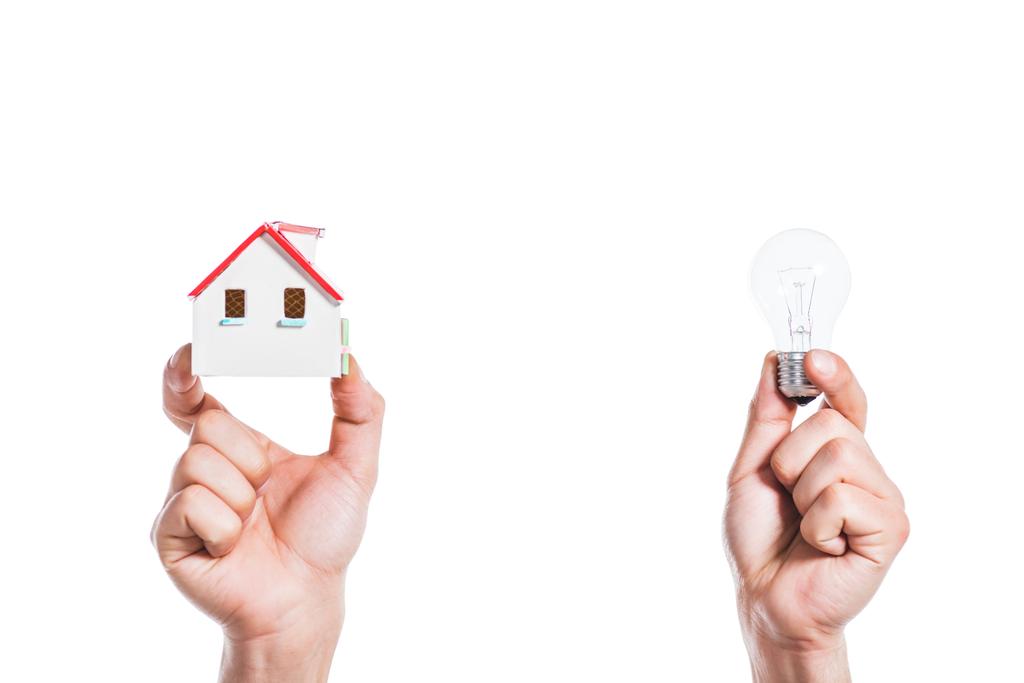 vista ritagliata di mani maschili che tengono modello di casa e lampada a led in mani isolate su bianco, concetto di efficienza energetica a casa
 - Foto, immagini