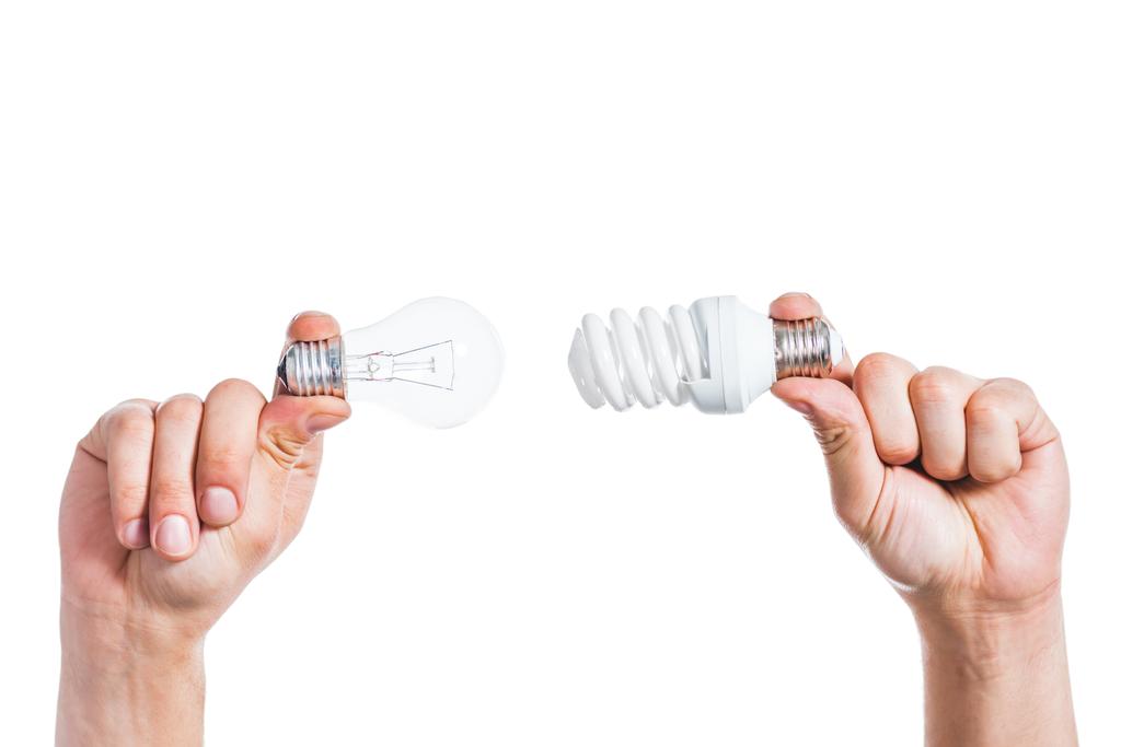 обрезанный взгляд на выбор между свинцовыми и флуоресцентными лампами в мужских руках, изолированных на белом, концепция энергоэффективности
  - Фото, изображение