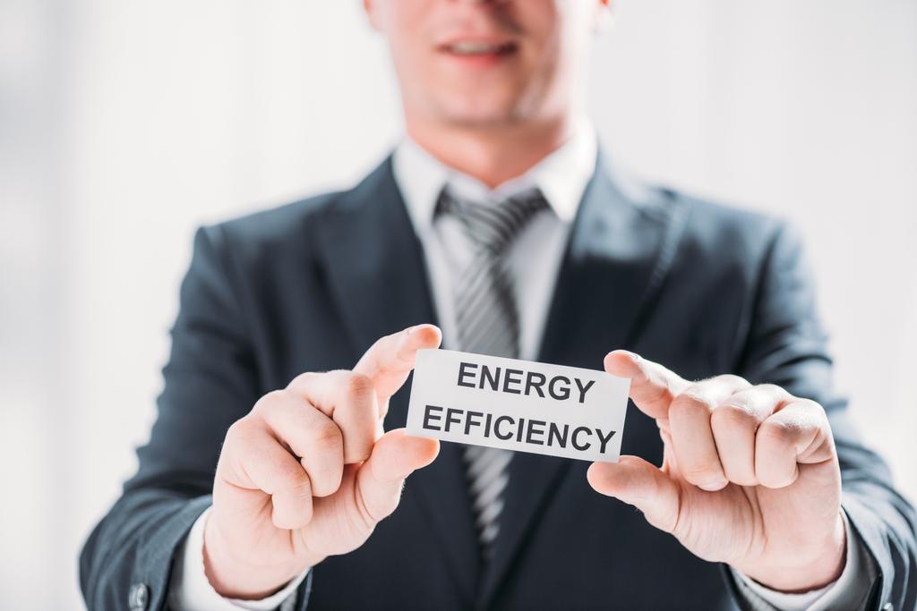 Selektywny fokus mężczyzna ręce biznesmen posiadający kartę z napisem na białym tle, pojęcie efektywności energetycznej - Zdjęcie, obraz