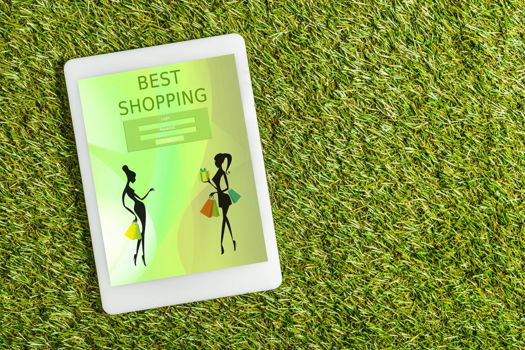 vista superior de la tableta digital con la aplicación de compras en la pantalla en césped verde, concepto de eficiencia energética
 - Foto, Imagen