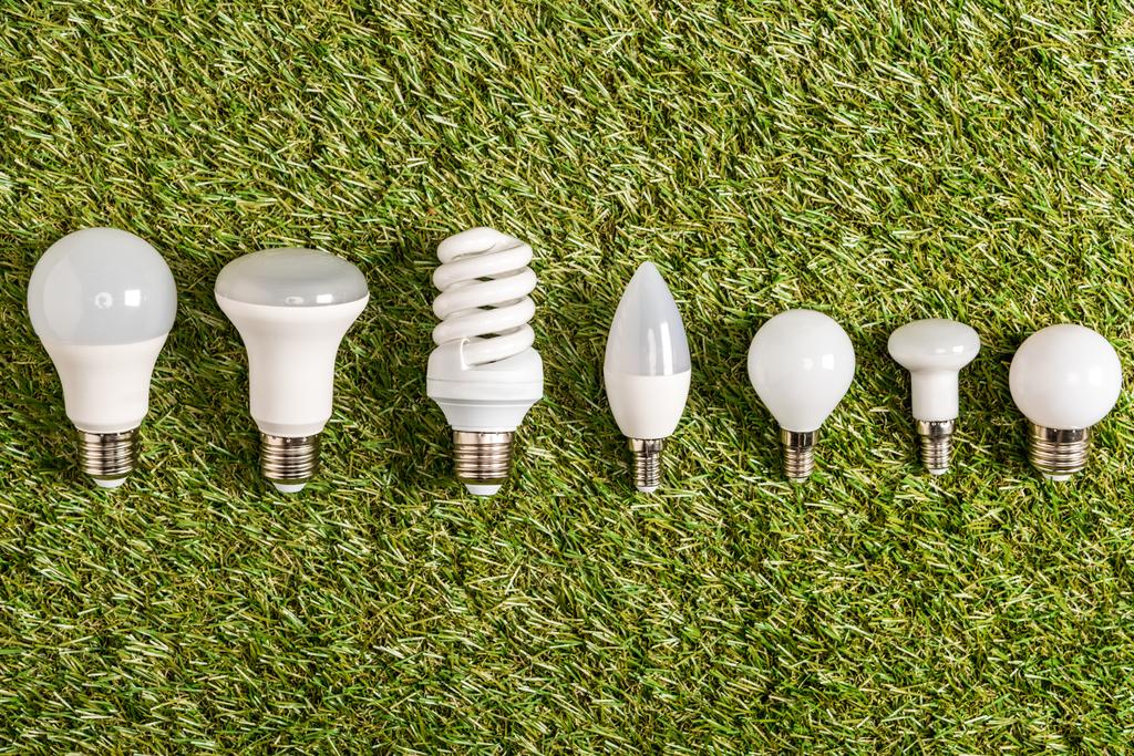 エネルギー効率の概念、緑の草の上の蛍光灯のフラット レイアウト - 写真・画像