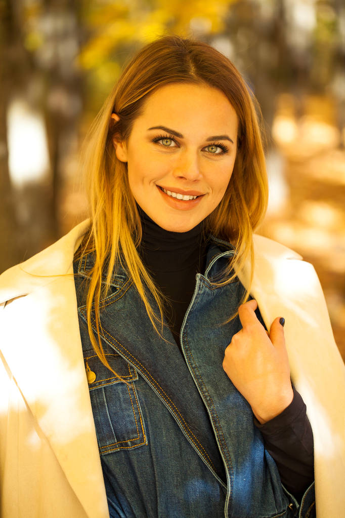 Портрет молодої красивої блондинки в сірому пальто на фоні осінньої вулиці
 - Фото, зображення