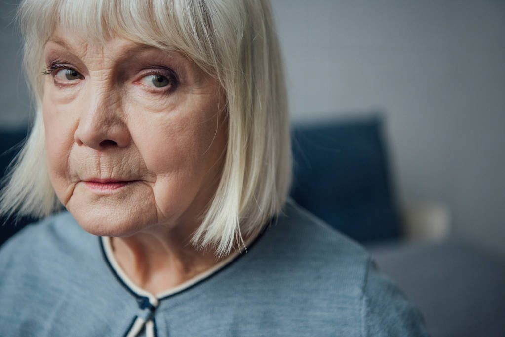 портрет засмученої старшої жінки, яка дивиться на камеру вдома
 - Фото, зображення