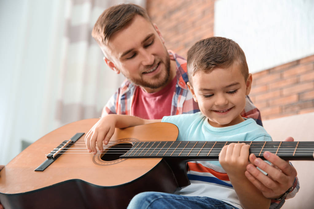 Père enseignant à son petit fils à jouer de la guitare à la maison
 - Photo, image
