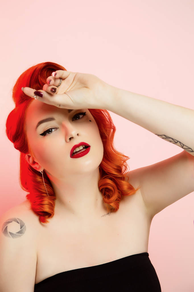 Portrait d'une belle fille aux cheveux roux avec pin up maquillage et cheveux en studio, fond de couleur, émotions
 - Photo, image