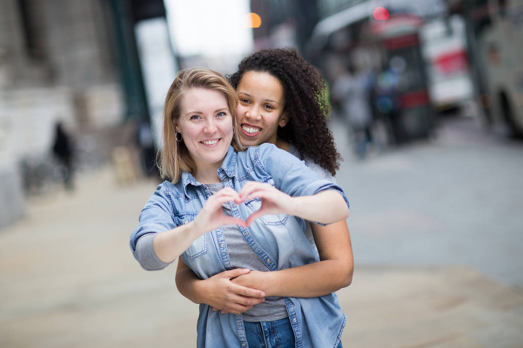 Lesbian couple showing a heart shape symbol with their hands - Photo, Image