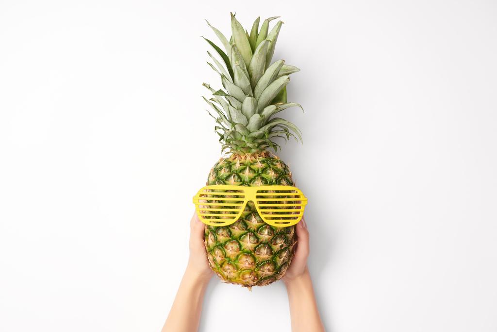 vista ritagliata di donna che tiene ananas in occhiali da sole su sfondo bianco
 - Foto, immagini