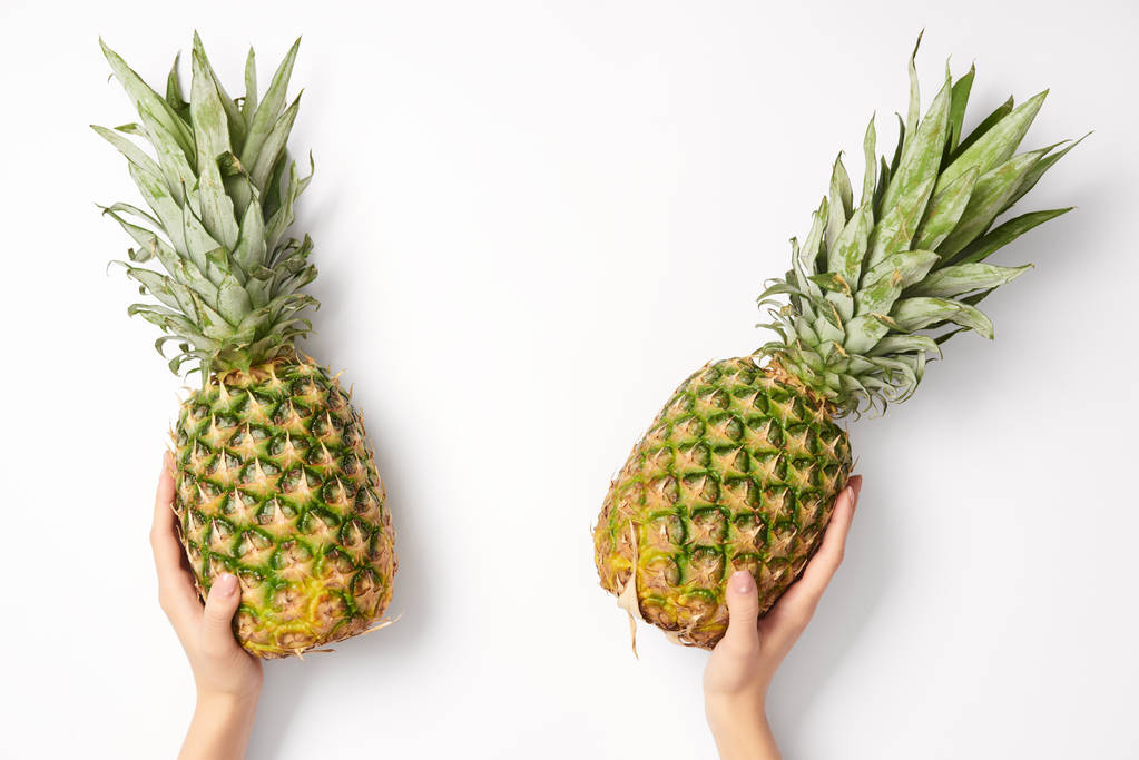 levágott nézet nő ananász tartja kezében a fehér háttér - Fotó, kép