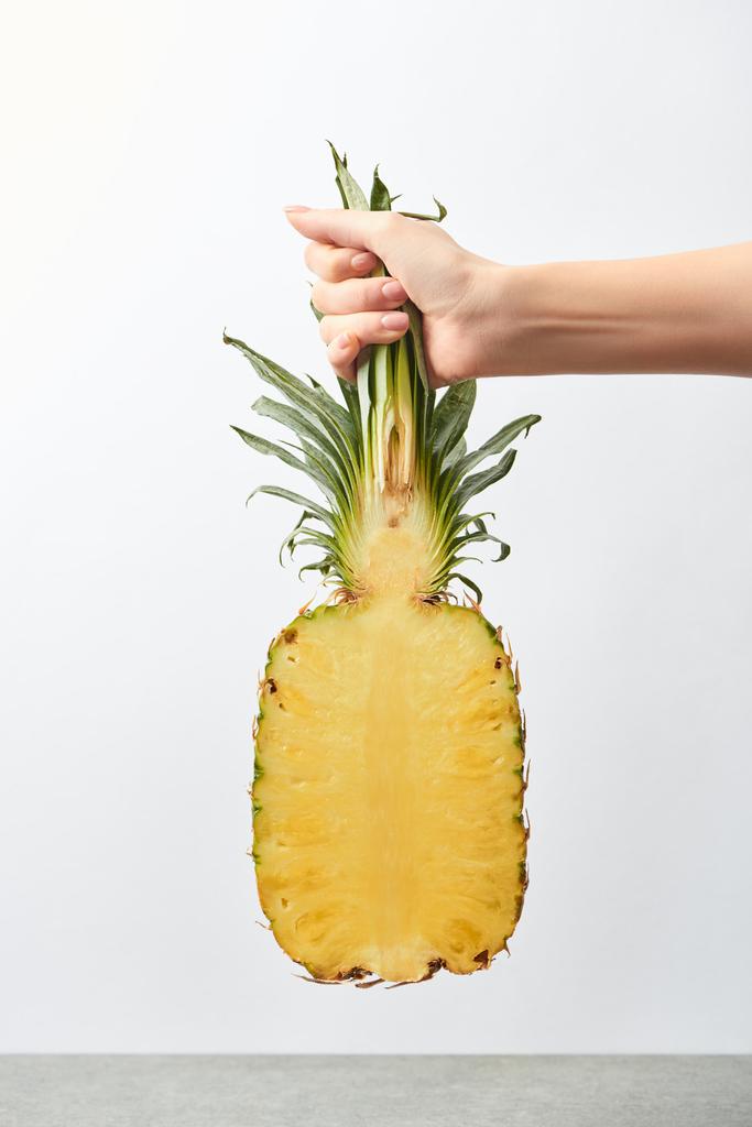 abgeschnittene Ansicht einer Frau, die eine gelbe Ananas halb in der Hand hält, isoliert auf weiß - Foto, Bild