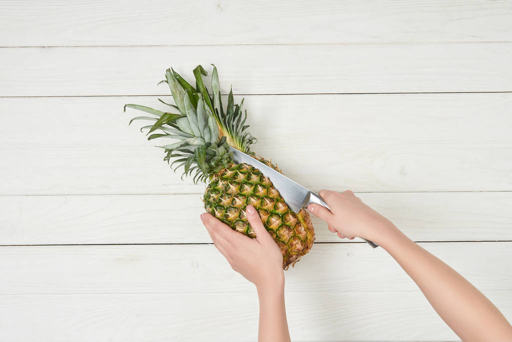 abgeschnittene Ansicht einer Frau, die Bio-Ananas mit Messer schneidet  - Foto, Bild