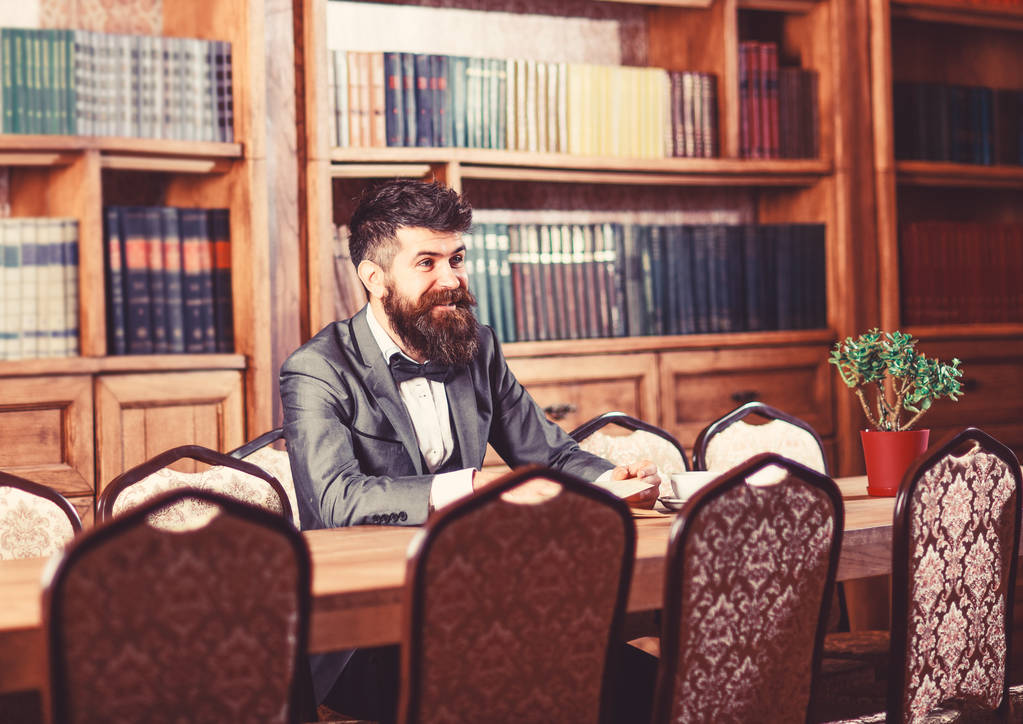 Потрясающий бизнесмен в домашней обстановке за столом и в книжных шкафах
 - Фото, изображение