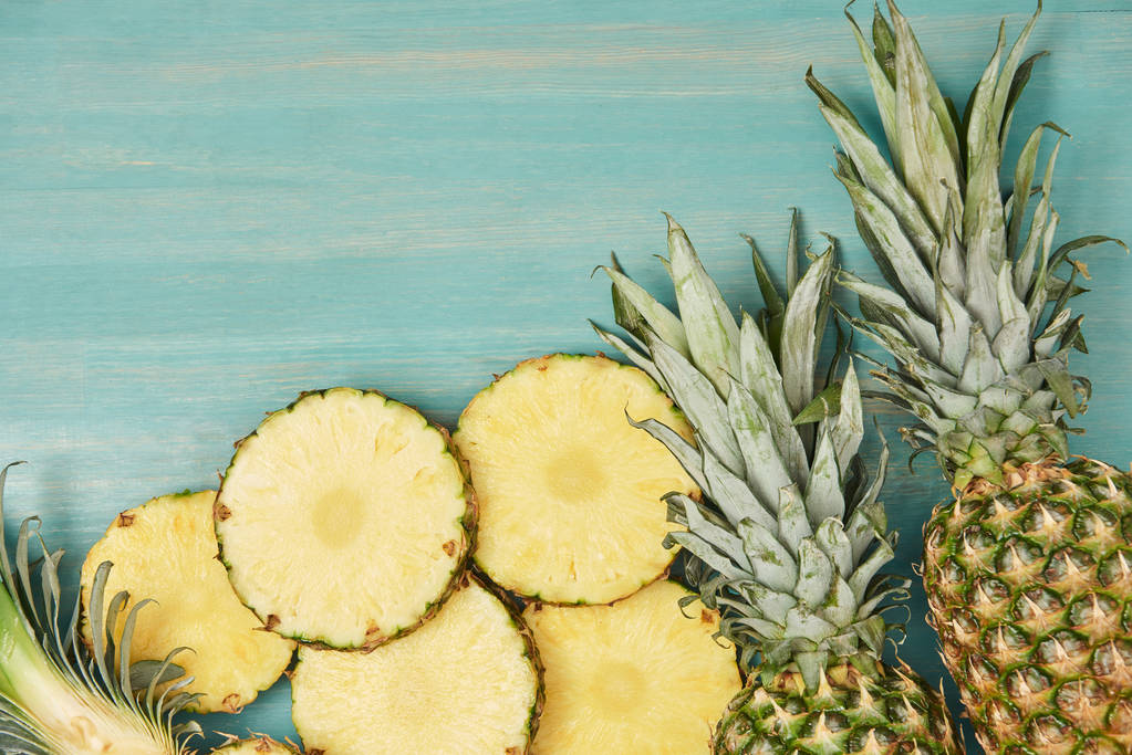 vista dall'alto di ananas affettati e interi su tavolo di legno turchese
 - Foto, immagini