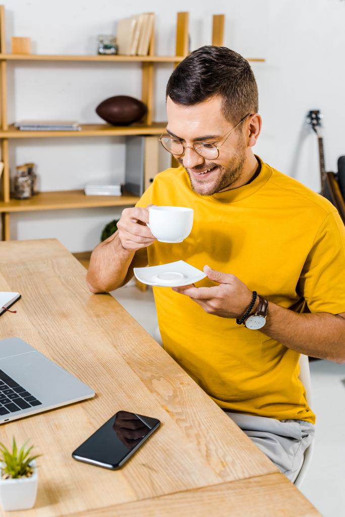 homme souriant dans des lunettes regardant une tasse de café
  - Photo, image